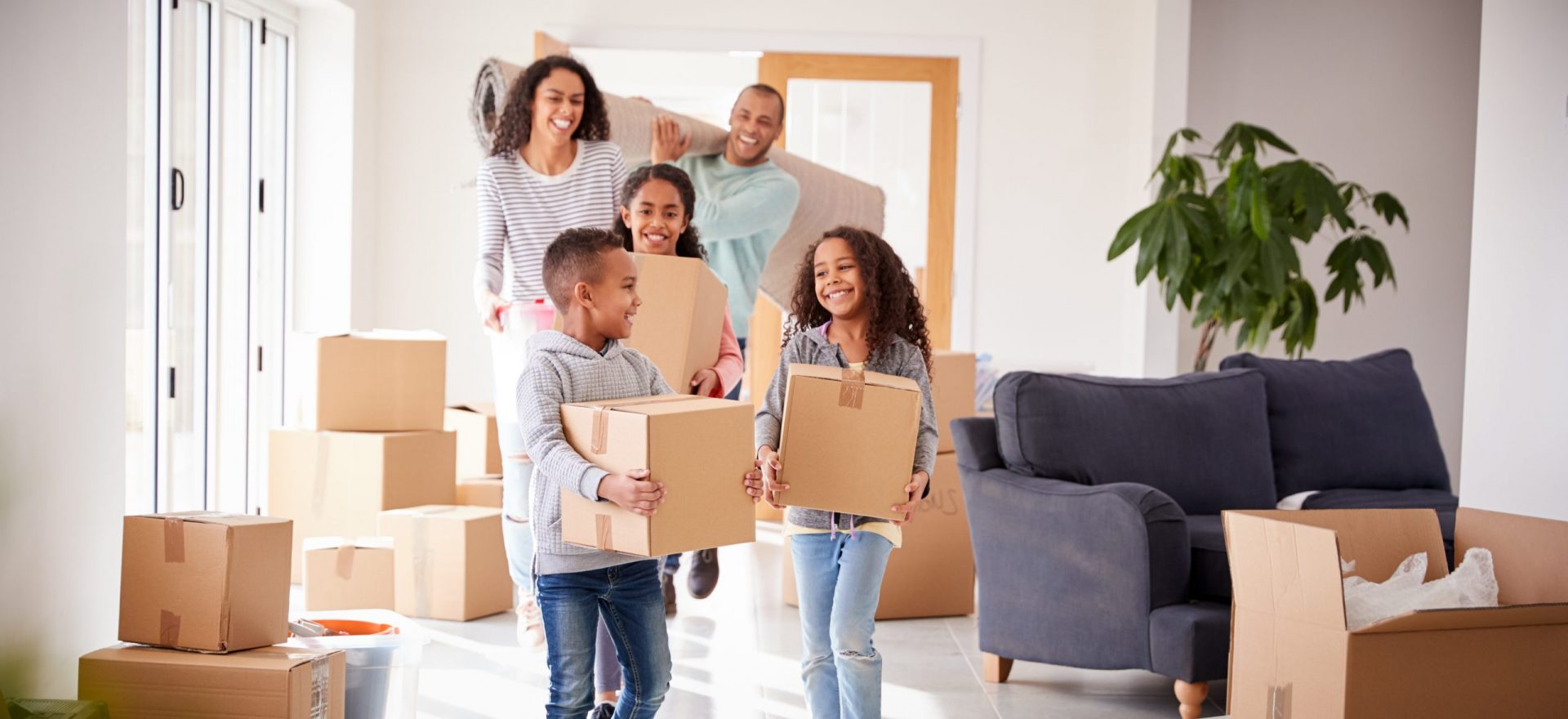Smiling Family Carrying Boxes Into New Home On Moving Day Smiling Family Carrying Boxes Into New Home On Moving Day